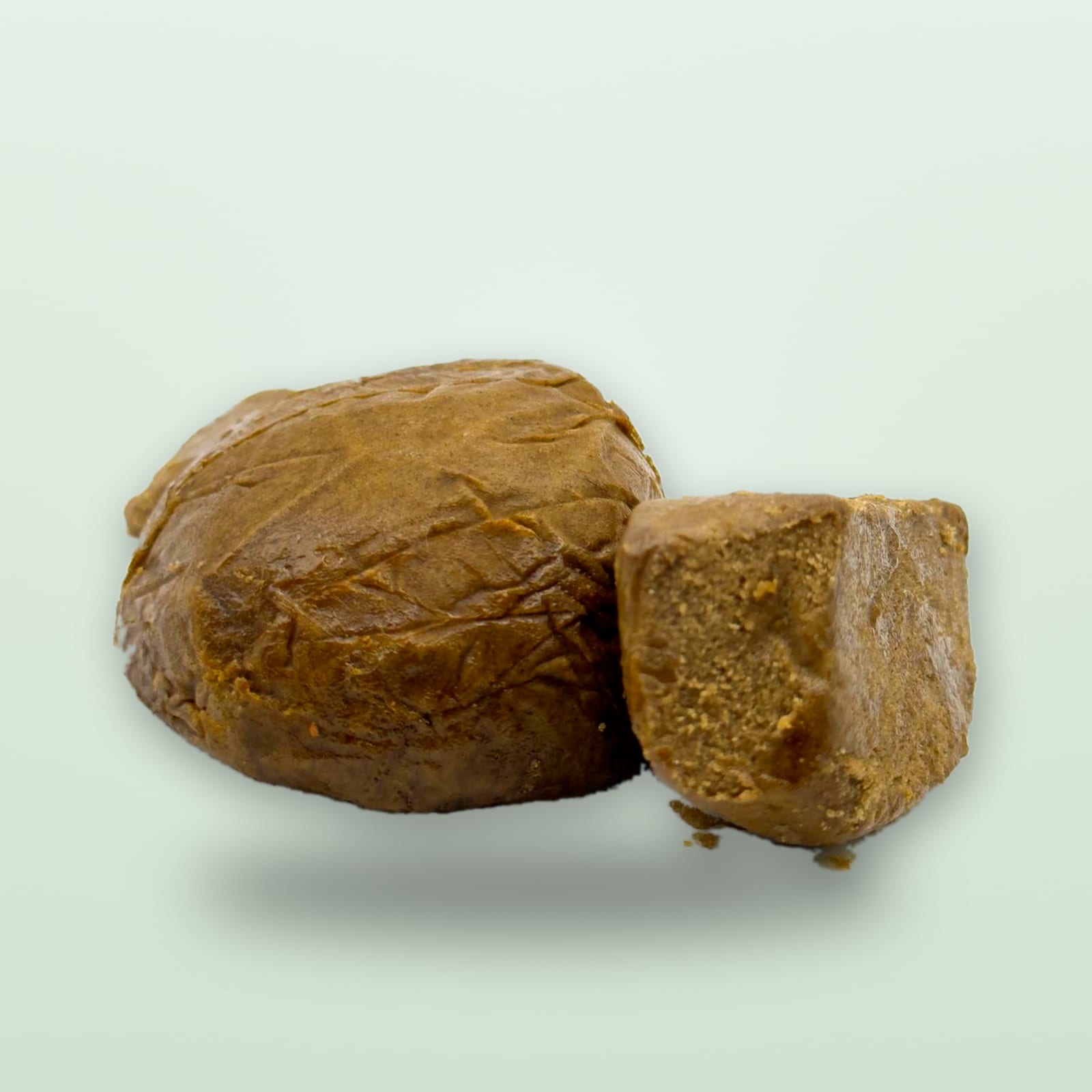 A block of brown resin and the piece cut from it, set side by side on a pale green background